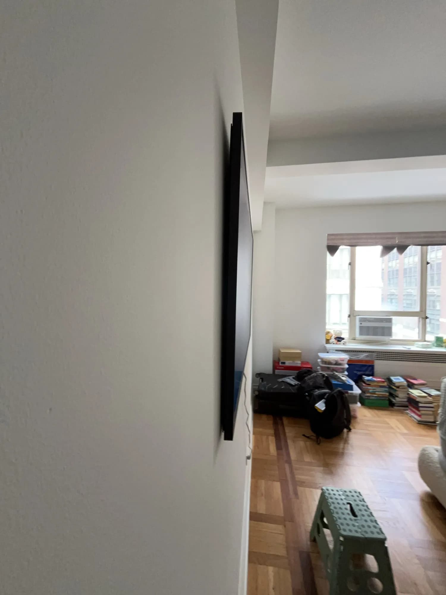 A side profile of a flush-mounted TV with a living room and window beyond.
