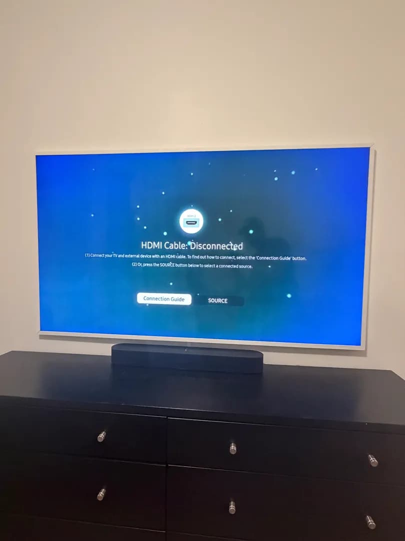 The Frame TV flush-mounted on the wall, powered on, with a soundbar on the dresser below.